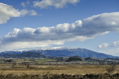Güneşli kış gününde, karlı dağın tepesinde beyaz bulutlar