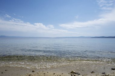 Gökyüzünde bulutlar olan güzel, sakin, mavi deniz.