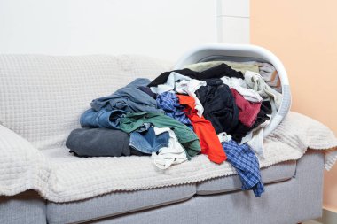 Koltuğun üzerinde bir yığın giysi olan plastik bir küvet.