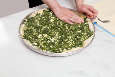 Mutfakta ıspanaklı turta hazırlayan kadın.