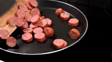 Kızartma tavasına çiğ sucuklu sosis döküyorum.