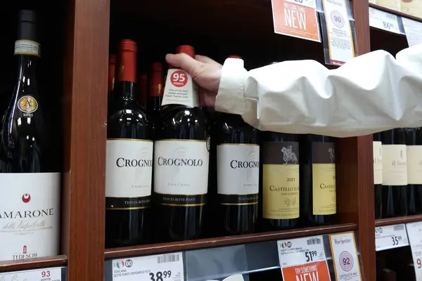 棚から赤ワインのボトルを取る手 ロイヤリティフリーのストック画像