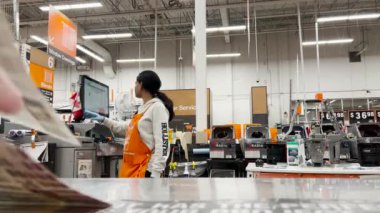 Home Depot mağazasının içinde 4k çözünürlüklü ev yenileme projesi için renk kartı etiketi veren bir işçi