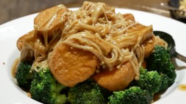 Lokantanın içindeki masada yumurta tofu üzerine pişirilmiş enoki mantarı hareketi 4K çözünürlüklü..