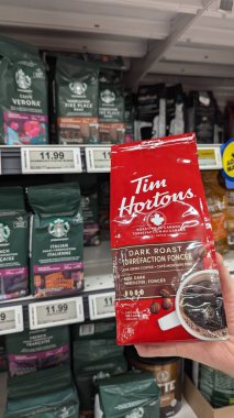 Starbucks kahve poşetinin önünde Tim Hortons 'ın kahve çekirdeklerini tutan bir el.