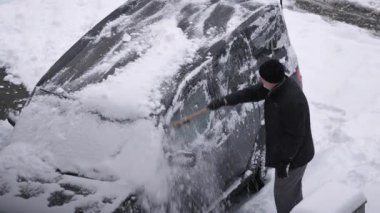 Sürücü karla kaplı otoparktaki arabadan karı temizledi