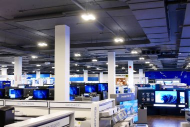 Modern bir elektronik mağazasının geniş açılı görüntüsü, çeşitli yeni televizyon görüntülerini gösteriyor..