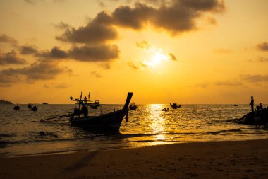 Yazın alacakaranlıkta Kalim Sahili 'nde güneş ve tekne Phuket Tayland