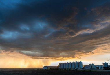 Gün batımında bir çiftliğe şiddetli yağmur yağması dramatik ve güzel bir manzara yaratır.