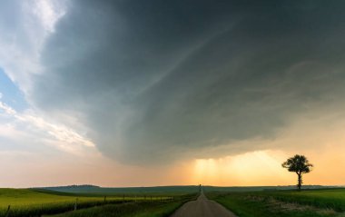 Gün batımında bir kır yolu üzerinde dramatik bir süper hücre fırtınası oluşuyor