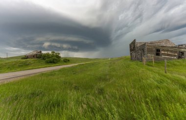 Terk edilmiş binalar ve bozkırlarda bir köy yolu üzerinde uğursuz süperhücre fırtınası bulutları oluşuyor.