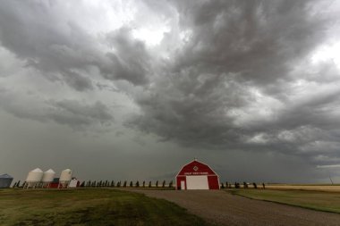 Uğursuz fırtına bulutları kırsaldaki bir çiftlikte kırmızı bir ahır ve siloların üzerinde toplanıyor.