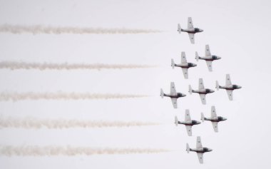 Dokuz askeri jet bir uçuş gösterisi düzenliyor. Düzen içinde uçuyorlar ve duman izi bırakıyorlar.