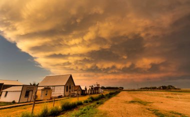 Çarpıcı memeli bulutları gün batımında küçük bir kırsal kasabada dramatik bir gökyüzü yaratır.
