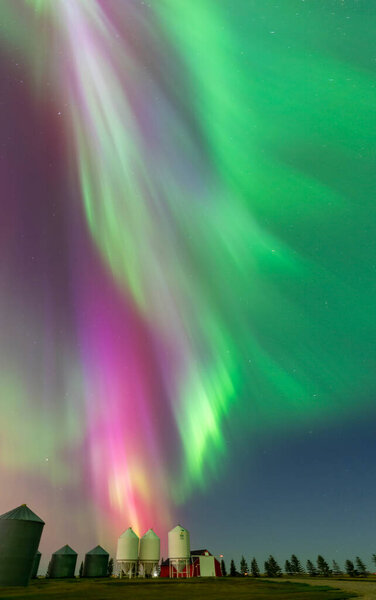 Northern lights illuminating farm silos in the night sky