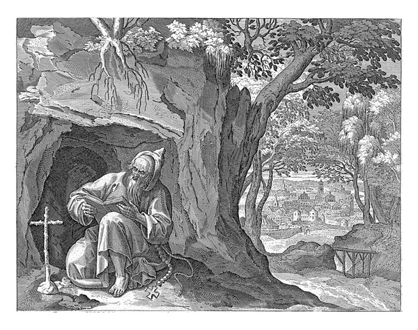 赫利阿斯是野外洞穴里的隐士 他正坐在十字架前 读一本圣经 以城市为背景的风景 — 图库照片
