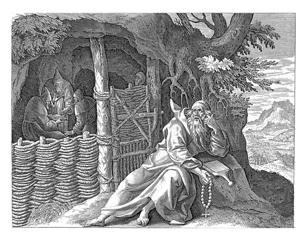 砂漠の洞窟の前にあるキプロスの聖スピリドン 彼は岩の上に横になって聖書を読んでいる 洞窟では3人の修道士が聖書を読んでいます — ストック写真