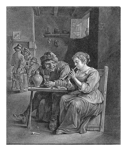 在一家客栈里 一位妇女坐在一位正在吹笛的农民旁边的桌旁 在后面的壁炉边喝着农民的酒 壁炉上方挂着印有半身像的印刷品或图画 — 图库照片
