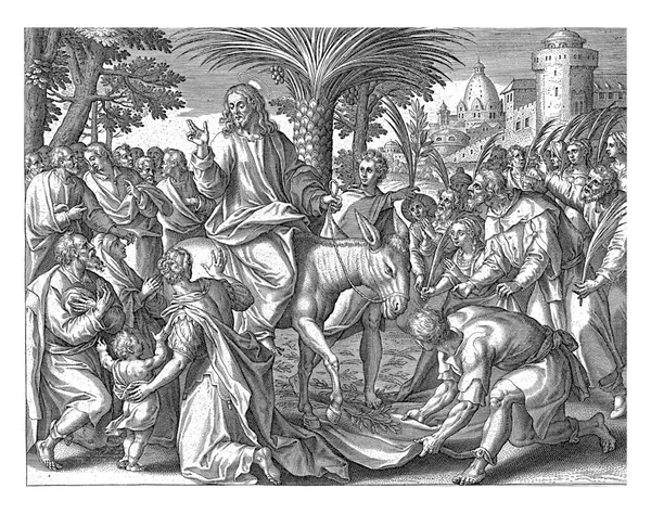 ロバに乗ってエルサレムに乗り込むキリスト 彼の周りの人々はヤシの枝を振る 男はキリストのために地面に彼のマントを置く — ストック写真