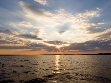 Su yüzeyi. Sunset gökyüzü arkaplanının görüntüsü. Gölün üzerinde akşam gökyüzü bulutları olan dramatik altın gün batımı gökyüzü. Temiz su dokusu. Manzara. Su yansıması