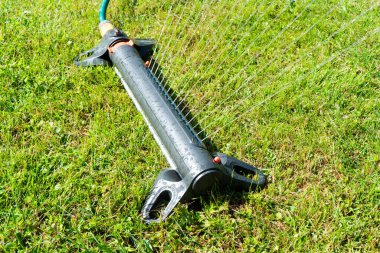 Bahçe sulama sistemi çimenliği. Otomatik çim püskürtücü yeşil çimenleri su damlalarıyla suluyor. Çim püskürtücü yeşil çimlerin üzerine su döker. 