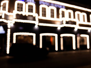 Arka plan bulanık. Gece şehri. Bulanık binalar, parlayan fenerlerin bokeh noktaları. Şehir caddesinin bulanık görüntüsü. Bokeh etkisi. Sokak lambaları Bokeh bulanıklığıyla dolu bir gece sokağı.