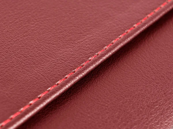 Red leather texture with red stitching. Part of perforated leather details. Red perforated leather texture background. Texture, artificial leather with diagonal red red stitching.