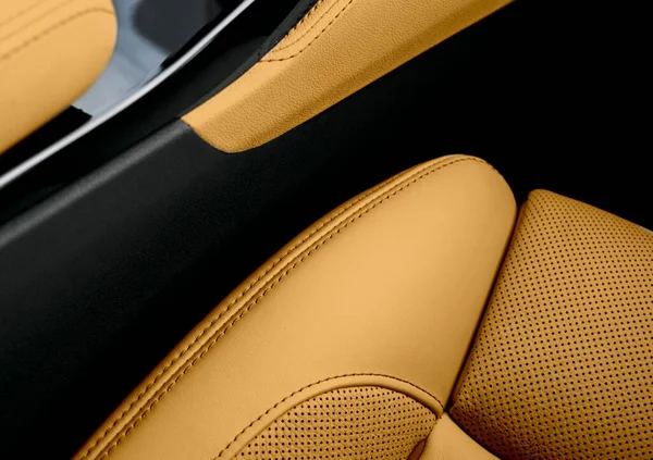 Modern luxury car brown leather interior. Part of perforated leather car seat details. Brown perforated leather texture background. Texture, artificial leather with stitching. Perforated leather seats