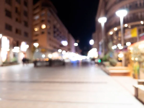 Blurred background. Night city. Blurred silhouette of buildings, bokeh spots of glowing lanterns. Blurred view of city street.Bokeh effect. Defocused night street with bokeh blur of street lights