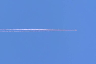 Flying airplane on blue sky background. Airplane flying in the blue sky sunlight. Trace from the plane