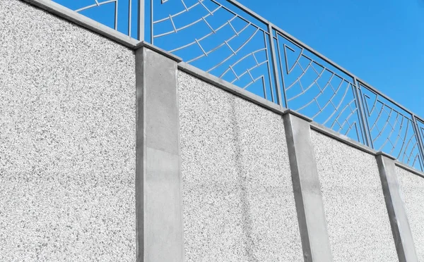 Modern stone and steel fence around the house over blue sky. Design and architecture of a modern house.