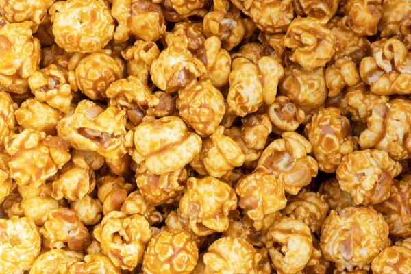 Caramel popcorn background texture. Popcorn pattern. Heap of delicious popcorn. Scattered popcorn texture background