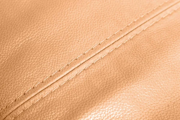 Car brown leather interior. Part of orange perforated leather car seat details with white stitching. Interior of prestige car. Comfortable perforated leather seats. Perforated leather.