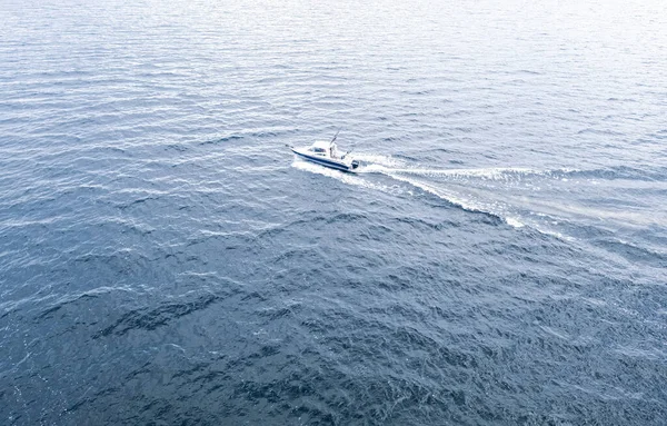Aerial view fisherman on boat at the ocean. Top view beautiful seascape with the fishing boat. Aerial view fishing motor boat with angler. Ocean sea water wave reflections. Motor boat in the ocean.