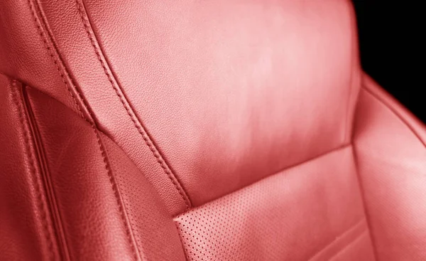 Modern luxury red leather interior. Part of red leather car seat details with stitching. Interior of prestige car. Comfortable red perforated leather seats. Perforated leather.