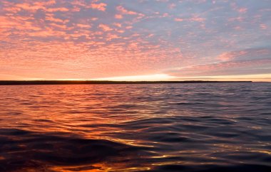 Su yüzeyi. Sunset gökyüzü arkaplanının görüntüsü. Gölün üzerinde akşam gökyüzü bulutları olan dramatik altın gün batımı gökyüzü. Temiz su dokusu. Manzara. Su yansıması