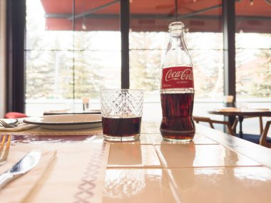 Yerevan, Armenia, February 28, 2023: Photo of can of Coca-Cola Classic glass bottle and cup in restaurant. Coca-cola bottle and coca cola in glass. 