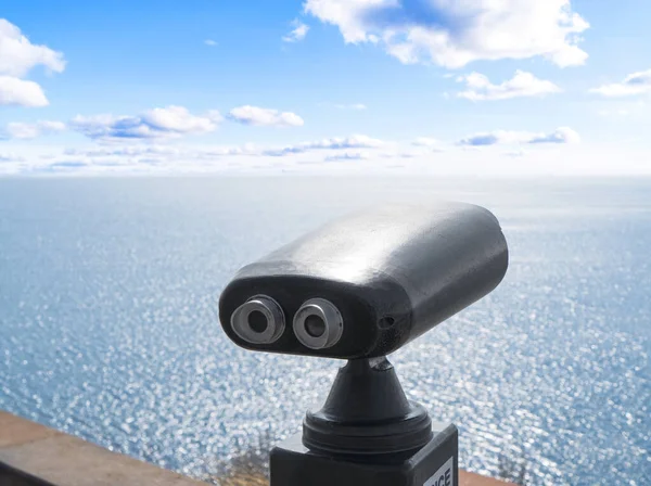 Tourist binoculars. A viewing platform for tourists. Stationary viewing binoculars. Binocular telescope on the observation deck for tourism. Sea background.