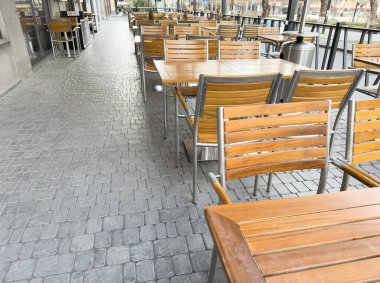 Bir Avrupa şehrinde boş, şık bir sokak kafesi. Sokak restoranı. Teraslı. Boş kafe masaları ve sandalyeler. Kafe restoranının dışında.