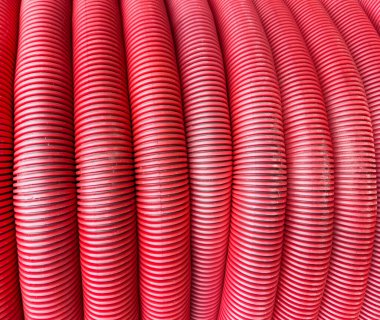 HDPE kıvrımlı boru dokusu arka planı. Yeraltı kablosunu korumak. Yuvarlak kırmızı PVC boru. Kırmızı borular. Örtülü inşaat borusu..