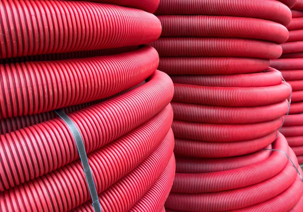 HDPE corrugated pipe texture background. Protection underground cable. Rolled up red corrugated PVC pipe. Red building pipes. Coated corrugated construction pipe.