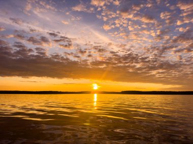 Su yüzeyi. Sunset gökyüzü arkaplanının görüntüsü. Deniz üzerinde akşam gökyüzü bulutları ile dramatik altın gün batımı gökyüzü. Kristal berrak deniz suyu dokusunun görüntüsü. Manzara. Küçük dalgalar. Su yansıması