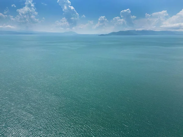 Aerial view of a blue sea water background and sun reflections. Aerial flying drone view. Waves water surface. Flight over the ocean. Aerial ocean view. Top fly over the sea.