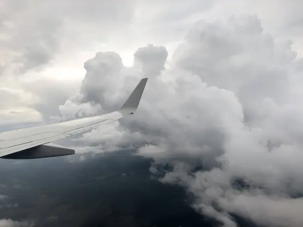 White wing from airplane window on stormy clouds. Great views of landscape. Aerial view of clouds through a plane window. Wing of airplane dark sky