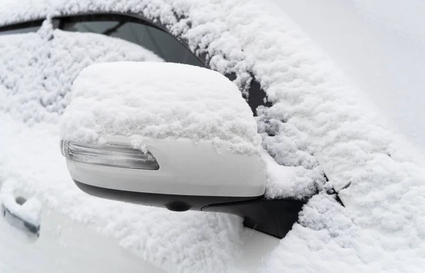Frozen car. Car covered with snow and frost. Part of the car under snow after a heavy snowfall. The body of the car is covered with snow after blizzard