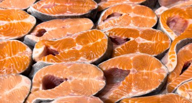 Taze somon bifteği dokusu. Somon balığı bifteği. Kocaman alabalık bifteği yığını. Büyük somon biftekleri sıraya dizildi. Büyük çiğ somon parçaları..