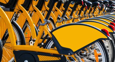 Bisikletler park halindeydi. Bir sıra park edilmiş renkli bisikletler. Kiralık bisikletler. Kaldırımda kiralanmak üzere klasik bisiklet kalıpları. 