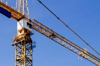 Mavi gökyüzü arka planında vinç kulesi. Turna ve bina çalışıyor. İşçi. İnşaat konsepti. Vinçli yeni binalar. Kule vinci