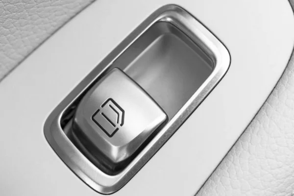 Car white leather interior details of door handle with windows control button. Car window controls of modern car.