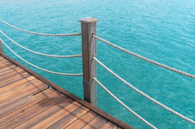 Sopalı ahşap iskele ve köpüklü deniz suyu olan halatlar. Mavi deniz zeminli ahşap iskele.. 